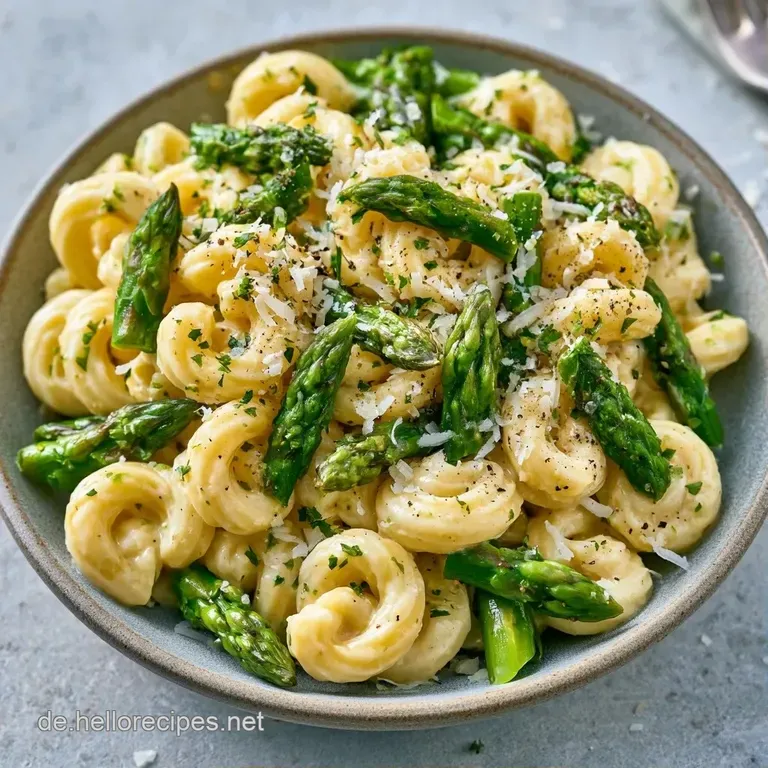 Gl&auml;nzende Pasta in wei&szlig;er Sauce auf einem schlichten Porzellanteller, garniert mit frischem, gr&uuml;nem Spargel.